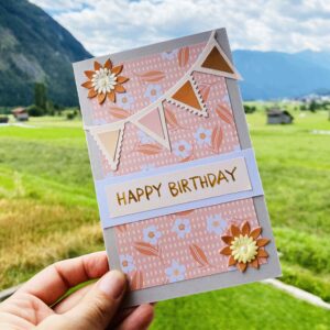 Eine Geburtstagskarte mit Papierelementen wie Blumen und einer Dreieck-Girlande zu einem Blogbeitrag über kreative Techniken.