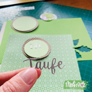 Zwei Finger die das Wort "Taufe" aus Papier halten in einem Blogbeitrag über das Basteln einer Taufkarte.